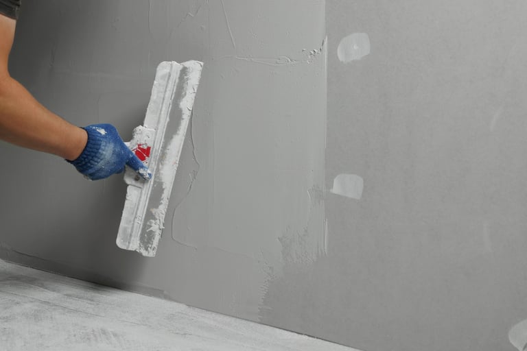 Professional worker plastering wall with putty knife, closeup