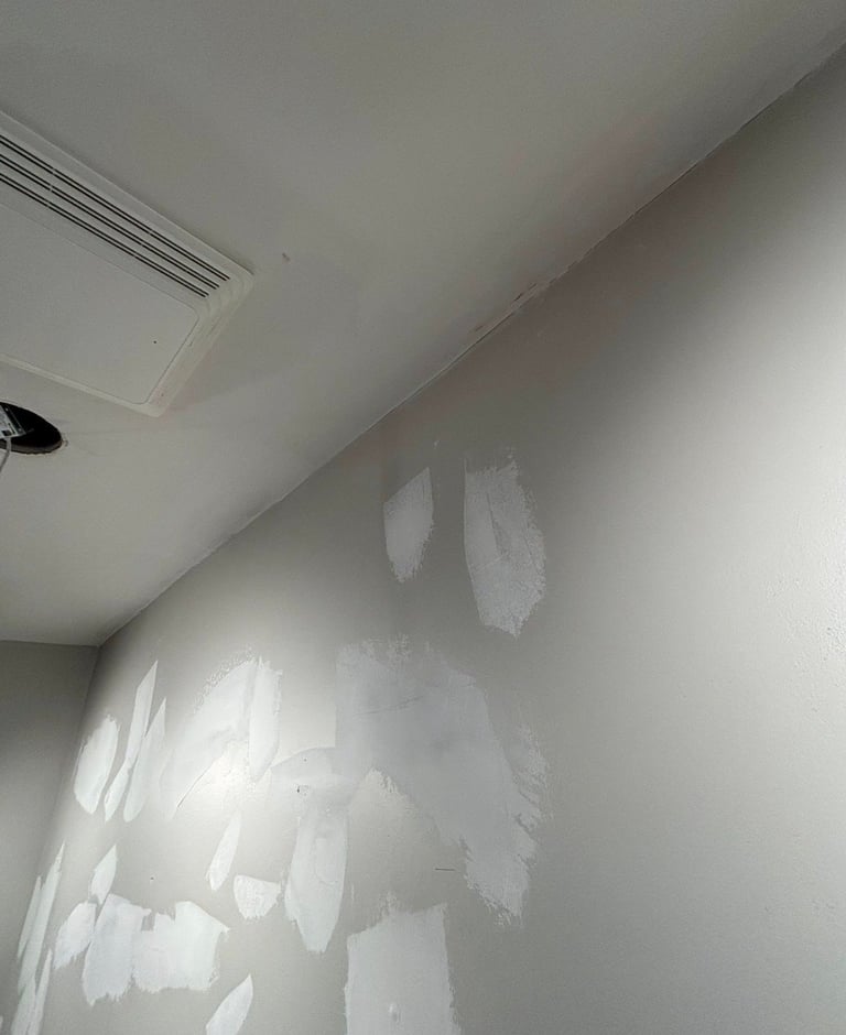 Interior wall with drywall patches and spackling compound applied, showing areas under renovation or repair