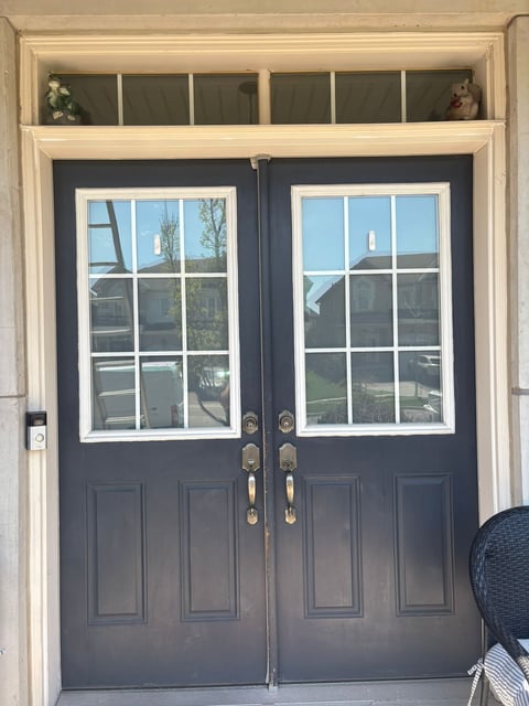 Elegant double glass and panel doors with dark blue-gray finish, cream trim, and transom window above