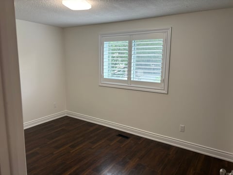 Empty room with beige walls and dark wooden floor
