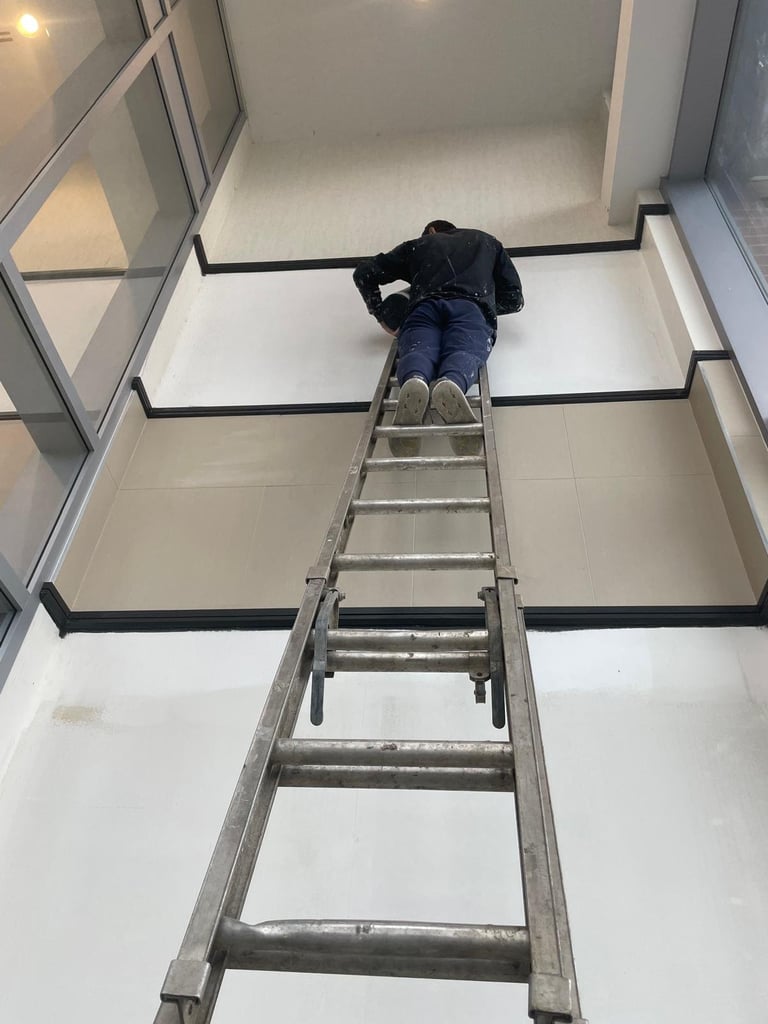 Person climbing a metal ladder up through an open ceiling or loft space indoors