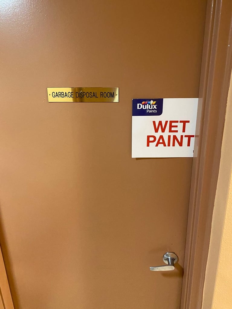 Door with two warning signs: Garbage Disposal Room label and Dulux Wet Paint sign